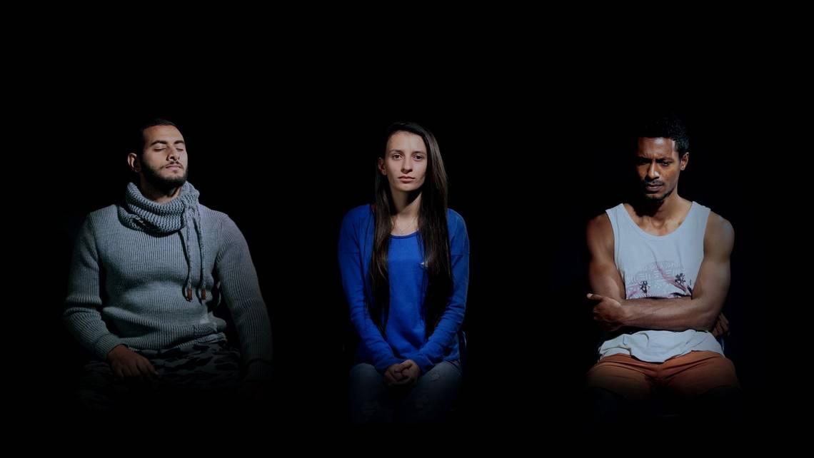 Video still of a man with his eyes closed, a woman looking neutral, and a man with arms folded, frowning. Filmed on a Canon EOS 5D Mark IV.